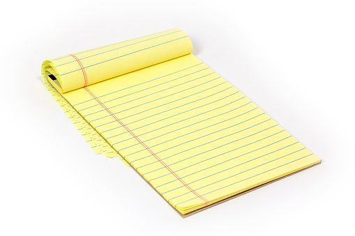 Note Pad with ruled yellow paper shot on a white background. The paper is yellow with a red margin line and blue rules. several pages have been flipped over the top, but there is no writing on the exposed page. A great office supply object that is blank and you can create your own message on it. There is a slight shadow cast from the pad, and is also easy to clip out the background.