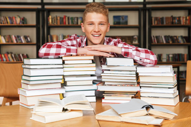 istock Smiling teenage boy sitting at the library table 1320350612