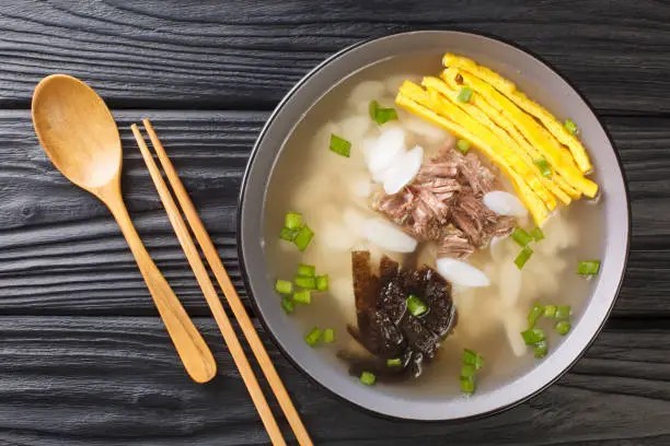 Photo of Tteokguk or sliced rice cake soup is a traditional Korean dish eaten during the celebration of the Korean New Year closeup in the bowl. Horizontal top view