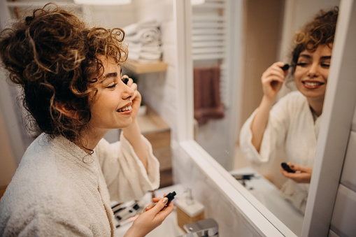 Young woman applying mascara in a bathroom