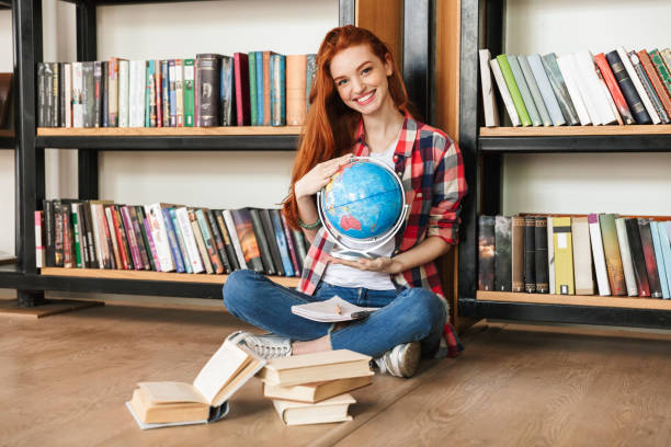 adolescente sorridente che tiene il globo - teenager globe women world map foto e immagini stock