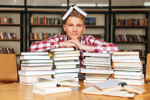 istock Smiling teenage boy sitting at the library table 1320351912