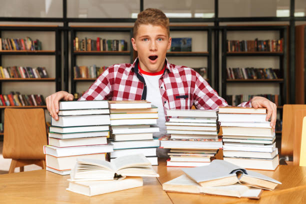 istock Shocked teenage boy sitting at the library table 1320351977
