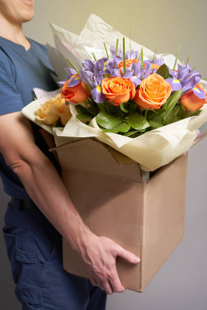 istock White male courier holding a large cardboard box with several bouquets 1320353811