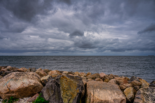 A beautiful, dramatic sky over the ocean. Stones in a wave breaker in the foreground. Picture from Malmo, Sweden
