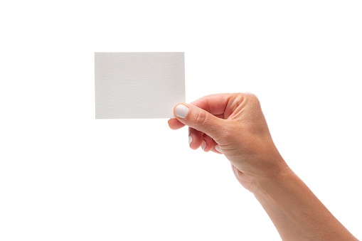 Close up view of a female hand holding a white blank card with the fingers isolated on white background. Copy space