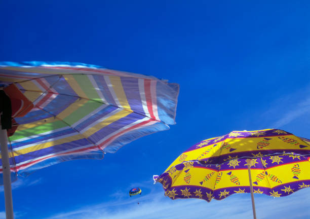 Couple parasailing seen through beach umbrellas, Miami Beach, Florida