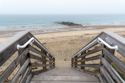 Empty wooden stairs to a deserted beach on a misty autumn day. Sandwich, Cape Cod, MA, USA.