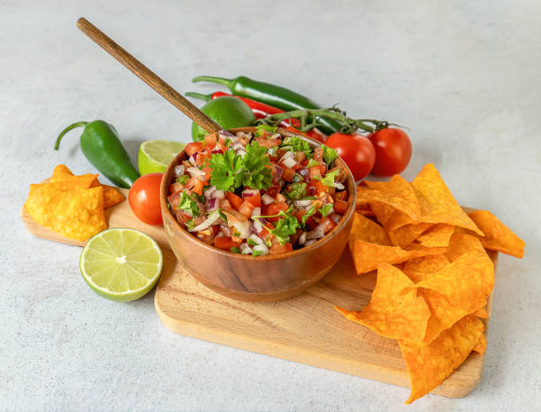 istock Mexican appetizer Pico de Gallo in a bowl and ingredients on the table. 1320360229