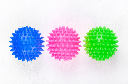 Three laundry balls for washing machine of blue, green and pink colors on white
