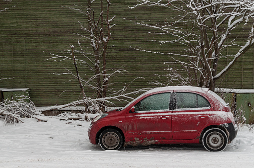 Petrozavodsk, Russia - 4 January 2021. red Volkswagen beetle in the parking lot near the green house on a winter day