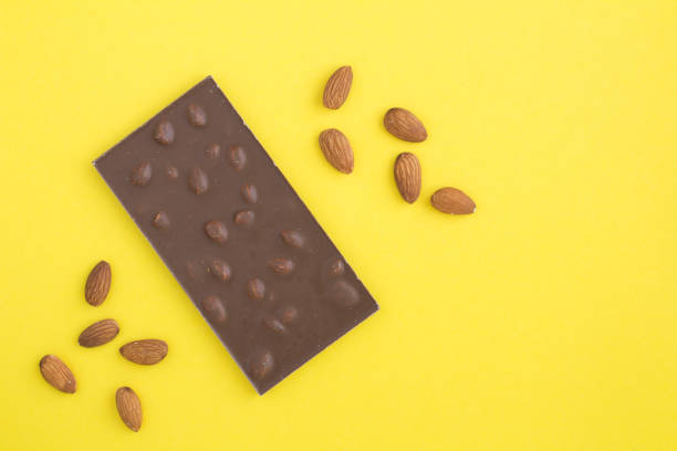 istock Milk chocolate with almond on the yellow  background. Top view. 1320363383