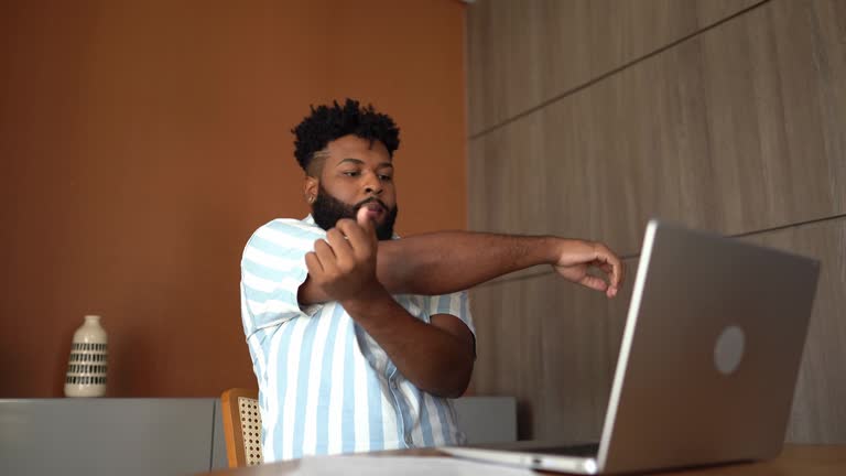 Young man stretching while working at home
