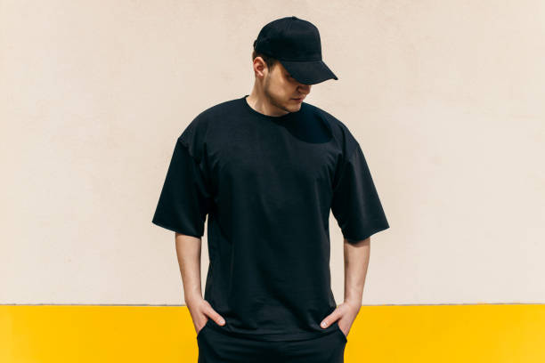 homme portant un t-shirt noir vierge et une casquette de baseball noire avec de l’espace pour votre logo ou votre design. maquette - sneering photos et images de collection