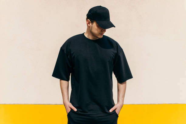 Man wearing black blank t-shirt and a black baseball cap with space for your logo or design. Mock up Man wearing black blank t-shirt and a black baseball cap with space for your logo or design. Mock up sneering stock pictures, royalty-free photos & images