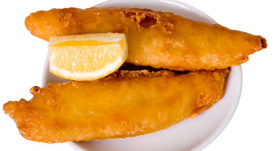Golden deep fried beer battered fish with a wedge of lemon. Isolated on white background.