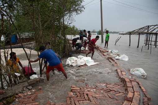 Due to cyclone Yas, a lot of water has risen in the river and the area is being flooded. People are trying to build dams to protect the area. Many people have died and more severe damage has been caused by such situations in the past. Koira, Khulna, Bangladesh. May 26, 2021