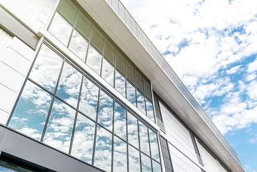 Facade of a modern office building made of glass and metal. Modern minimalist architecture. Building on a background of blue sky and clouds, background and texture