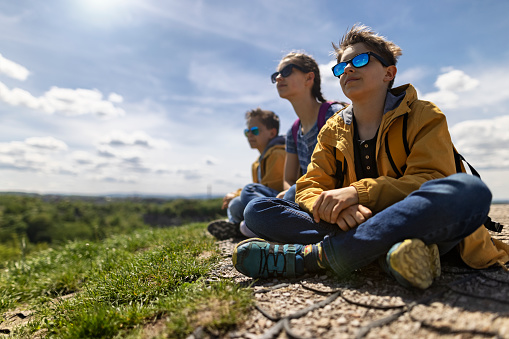 Three kids hikers have climbed the hill. They are sitting on the top of Krakus Mound hill, a famous place near Krakow.\nShot with Canon R5