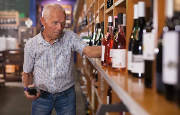 Mature man visiting winehouse in search of bottle of good wine