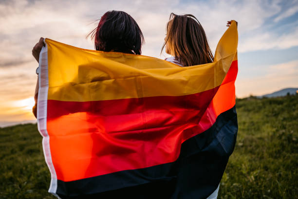istock Two women  covering themselves with German flag on meadow 1320378427