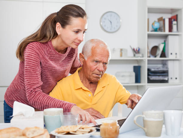 istock Mature man working at laptop, daughter trying to help him 1320378697