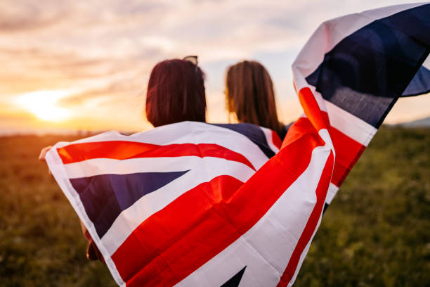 istock Two women  covering themselves with British flag on meadow 1320378750