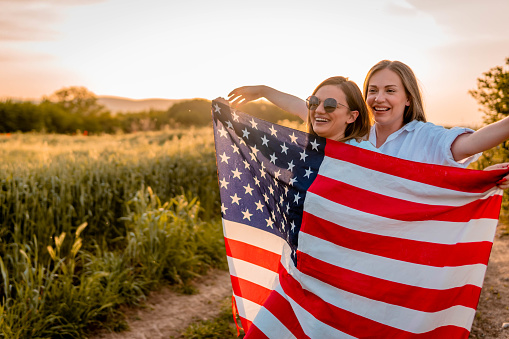 Young women celebrating 4th of july, holding American flag.
