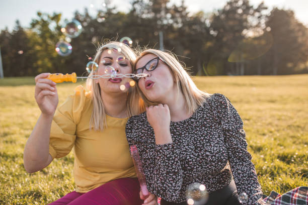 istock Two gorgeous ladies having fun making soap bubbles 1320379488