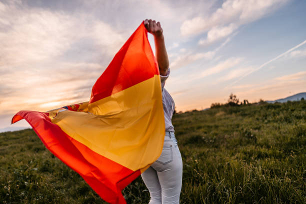 istock Woman spreading wide Spanish flag at sunset 1320379567