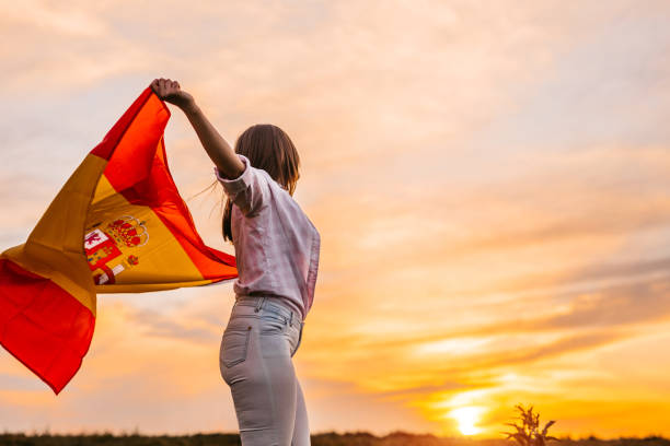 istock Woman spreading wide Spanish flag at sunset 1320379759