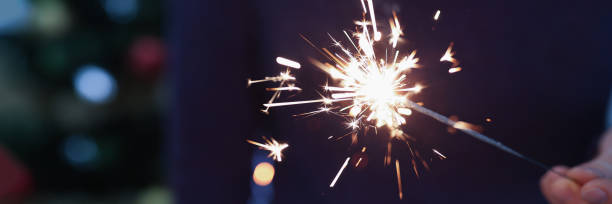 istock Man holding sparkler in hand for christmas closeup 1320382093