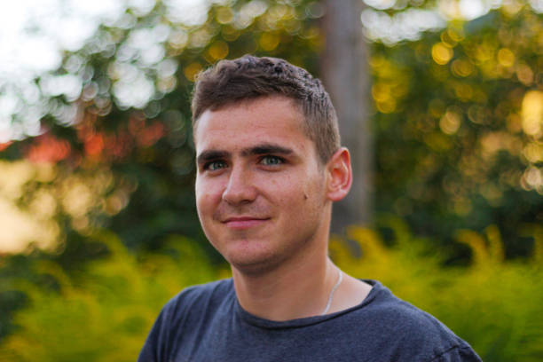 istock Defocus handsome caucasian young man outdoors portrait. Man smiling, looking in the camera. Blurred nature summer, nature background. Close-up guy 20 years old. Out of focus. 1320384394
