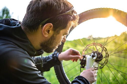 Handsome young man repair his bike in nature