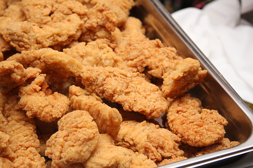 Chicken tenders or chicken fingers in a stainless steel tray.