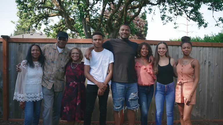 A large group of family members embraces in the backyard for a portrait, having not seen each other for a long time, due to normal circumstances or perhaps COVID-19 or Coronavirus.  Happiness and joy abound as they are together again.