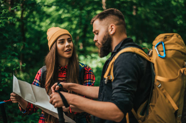 istock Couple of hikers using trekking poles and map while wearing backpacks 1320388541