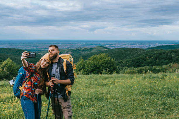 istock Hikers taking selfie with a smartphone and using trekking poles while wearing backpacks 1320388558