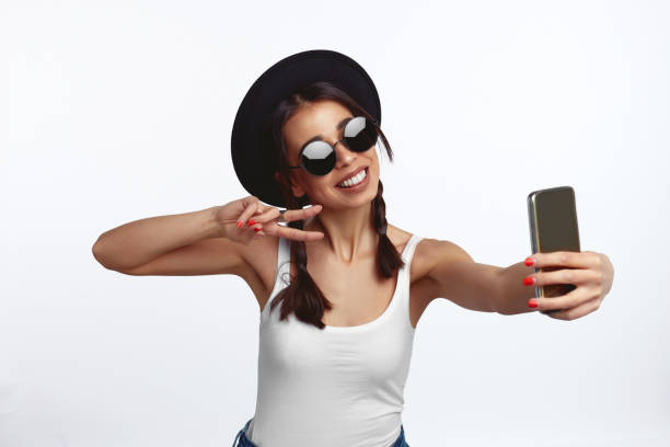 istock Cute girl taking selfie and showing peace gesture over white wall 1320389569