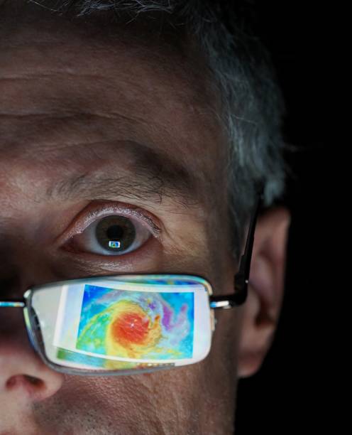 Meteorologist stares at impending hurricane in satellite image reflected on glasses