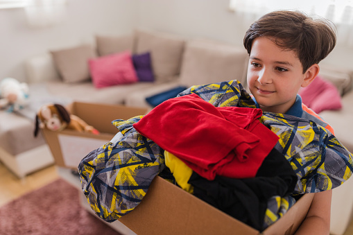 Happy young boy with a box of his old clothes