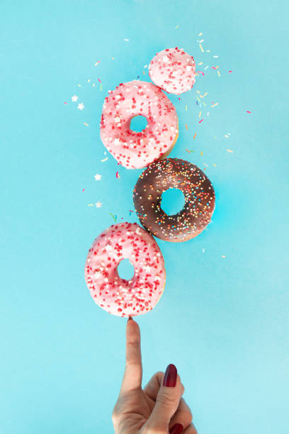 Strawberry and chocolate donuts levitating on finger.