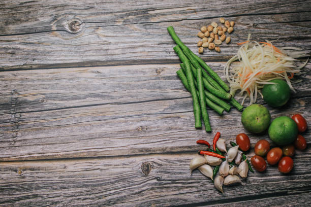 papaya salat (som tam) zutaten auf holztisch hintergrund. das berühmte lokale thailändische streetfood-gericht mit dem geschmack von heiß und würzig. - sour taste green traditional culture lemon stock-fotos und bilder