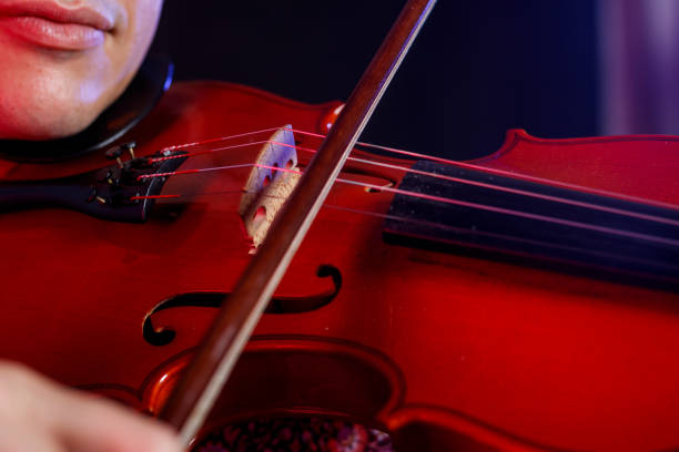istock Young man with violin on dark background 1320404888