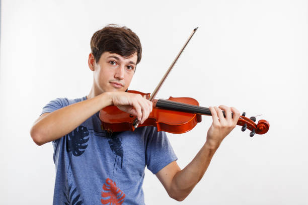 istock Musician playing violin while looking at camera. Stringed musical instrument. White background. Copy space. 1320404931