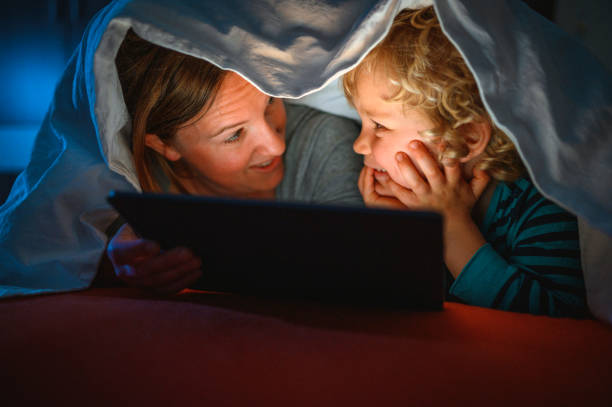 istock Cute blond boy and his mother using digital tablet at bedtime 1320407641