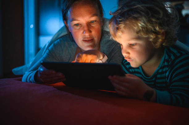 istock Cute blond boy and his mother using digital tablet at bedtime 1320407643