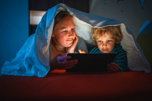 istock Cute blond boy and his mother using digital tablet at bedtime 1320407645