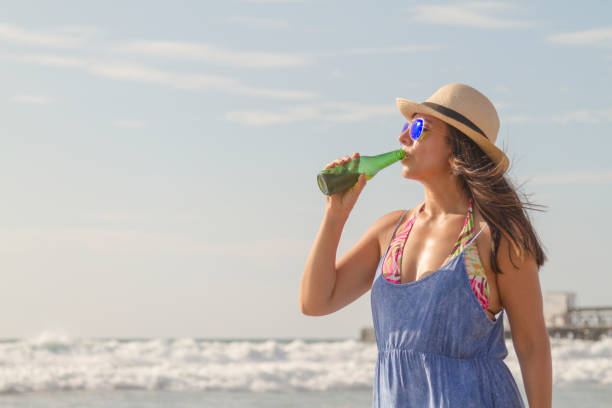 istock A single beautiful fit active young latin female Tourist backpacker drinking a cold bottle of beer at the beach. 1320416287