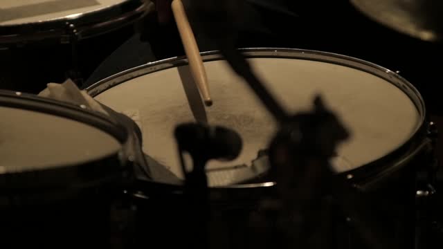 Drum kit getting played by a musician in a closeup.